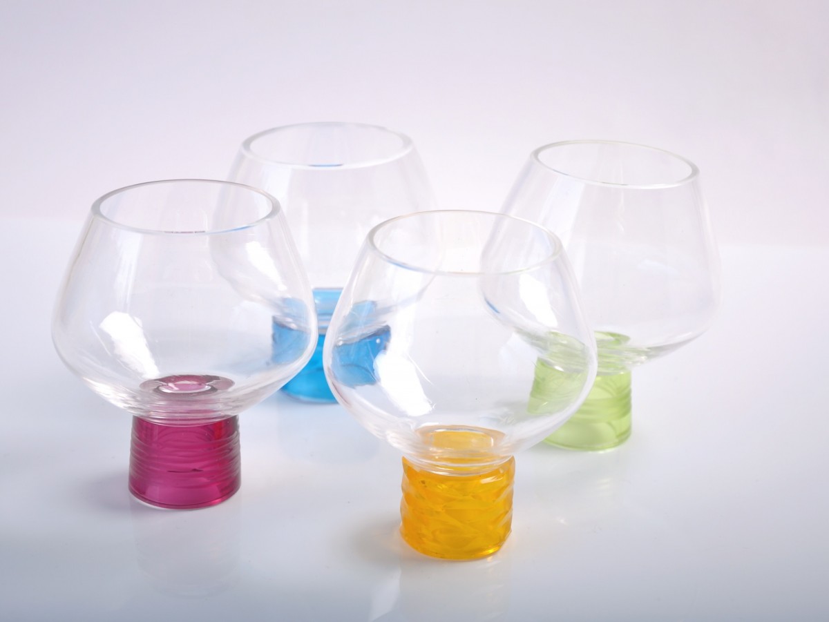 Four clear glass drinking glasses with coloured feet